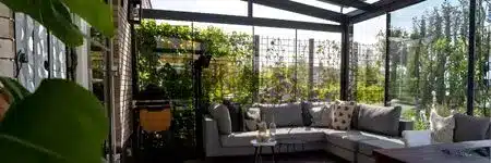 Fixed glass wall inside a veranda creating a bright, sheltered seating area.