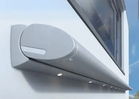 Compact Weinor Cassita II LED awning in grey, mounted on a white wall with built-in downlighting.